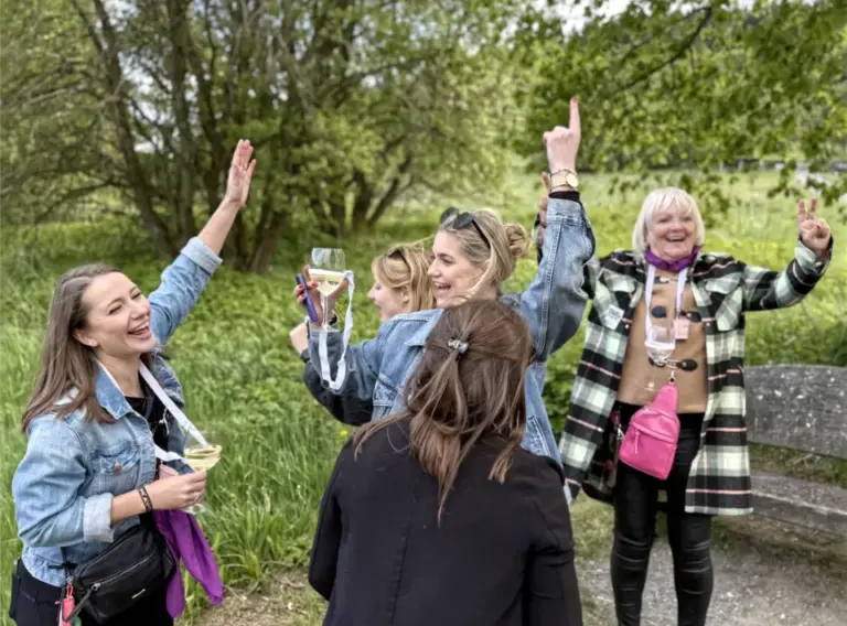 JGA-Event-Ideen-Singender-Junggesellenabschied Tanzende Frauen in der Natur von Willingen auf einem JGA Event mit Weingläsern in der Hand