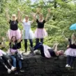 Gruppe aus Frauen beim Junggesellenabschied auf einer Schnitzeljagd mit den Händen in der Luft auf einer Mauer