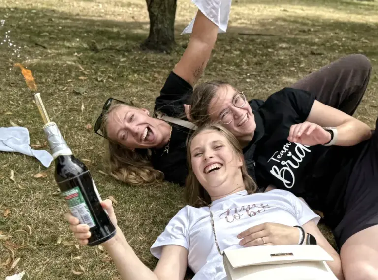 JGA-Ideen-Bierwanderung-Bierbike-Bierrallye Frauen auf Junggesellenabschied während der Siegerehrung beim JGA-Event in Venlo mit der Eventagentur "Deine Erlebnismacher", die lachend auf dem Boden liegen.