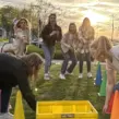 Frauen auf einem Junggesellenabschied mit der Braut die ein Spiel spielen und dabei Bleistifte in eine Kiste werfen