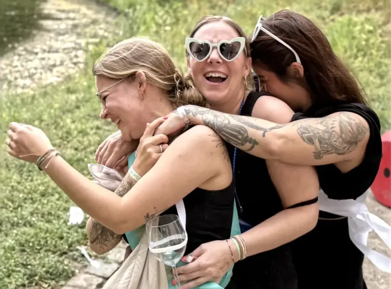 JGA-Sauerland-Karaoke-Junggesellenabschied-Willingen Tanzende Frauen auf Junggesellenabschied beim JGA-Event in Düsseldorf mit der Eventagentur "Deine Erlebnismacher", die sich in den Armen liegen und lachen.