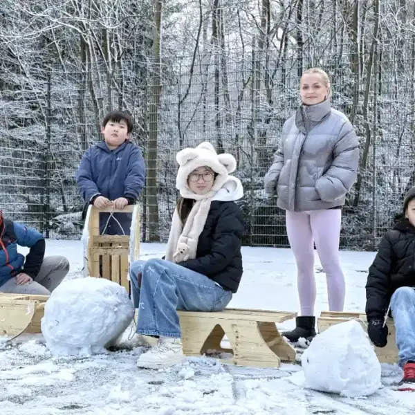 Kinder und Jugendliche bauen selbstgefertigte Holzschlitten und spielen im Schnee bei der Winterferien-Ferienbetreuung von deine Erlebnismacher