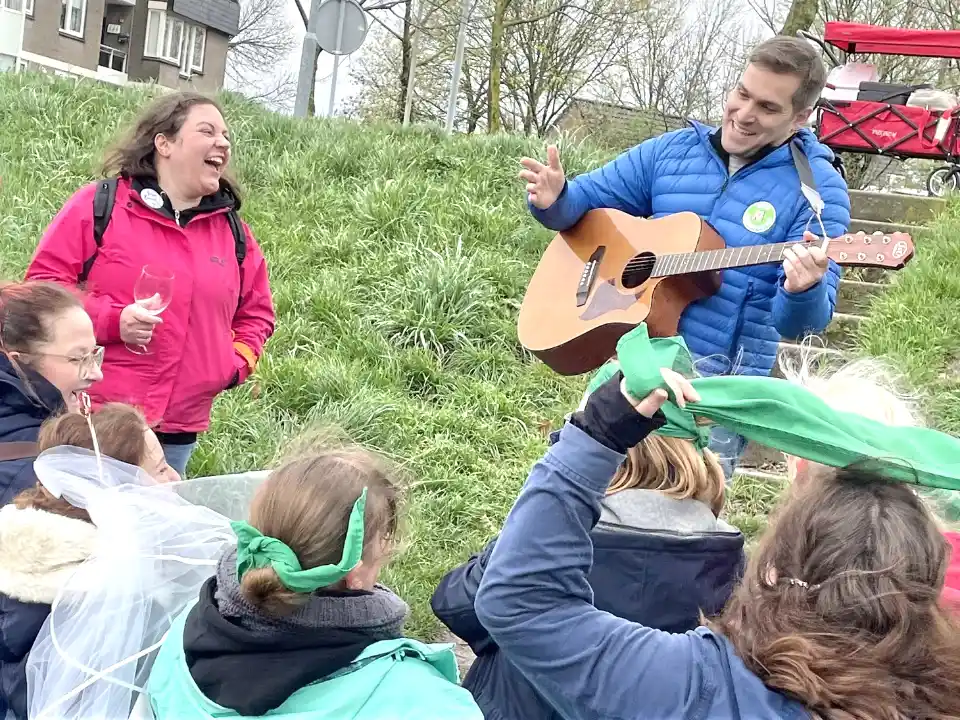 JGA singen: Gitarrist spielt live für eine fröhliche Gruppe beim musikalischen Junggesellinnenabschied