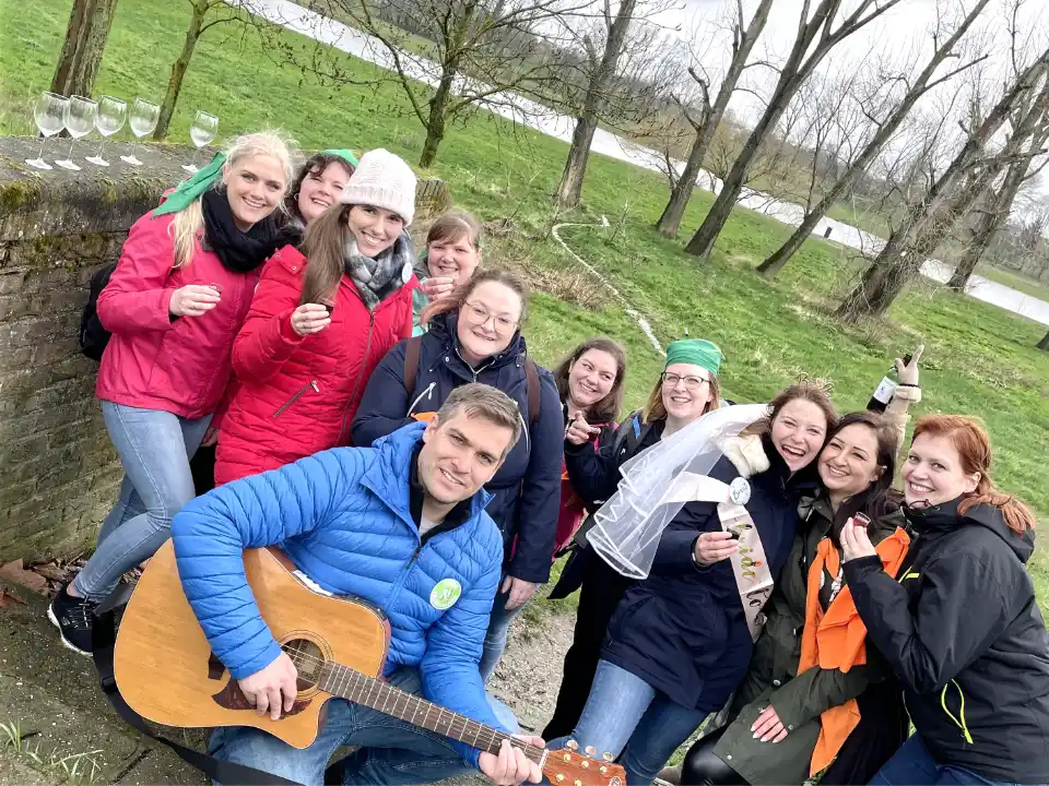 Gitarrist mit einer fröhlichen JGA-Gruppe beim Junggesellinnenabschied an der Maas in Venlo