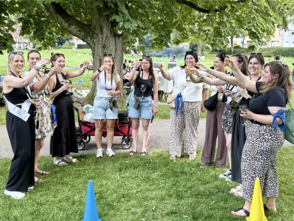 JGA-Gruppe bei einer Weinwanderung im Stadtgarten Essen. Die Teilnehmerinnen stoßen während der Weinrallye gemeinsam auf die Braut an.