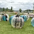Kinder in Bubble Soccer Bällen auf dem Kopf stehend beim Kindergeburtstag am Seaside Beach Baldeney in Essen