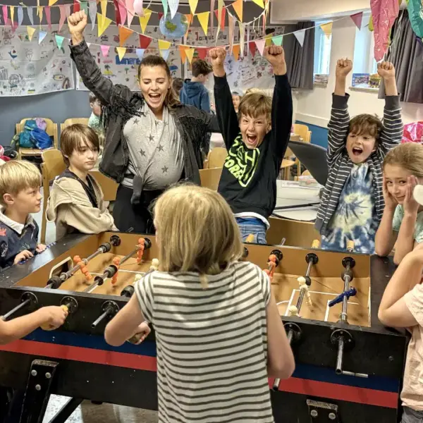 Kinder beim Jubeln am Kickertisch auf Ferienbetreuung in Essen bei Deine Erlebnismacher in der DJH Jugendherberge Essen-Werden.