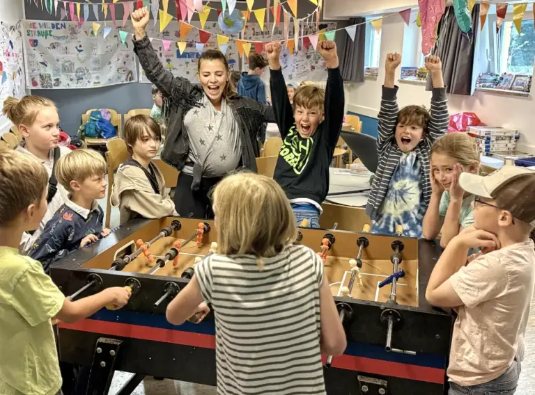 Kinder beim Jubeln am Kickertisch auf Ferienbetreuung in Essen bei Deine Erlebnismacher in der DJH Jugendherberge Essen-Werden.