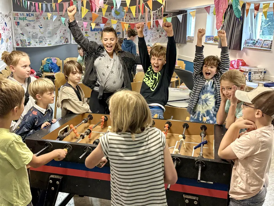 Kinder beim Jubeln am Kickertisch auf Ferienbetreuung in Essen bei Deine Erlebnismacher in der DJH Jugendherberge Essen-Werden.