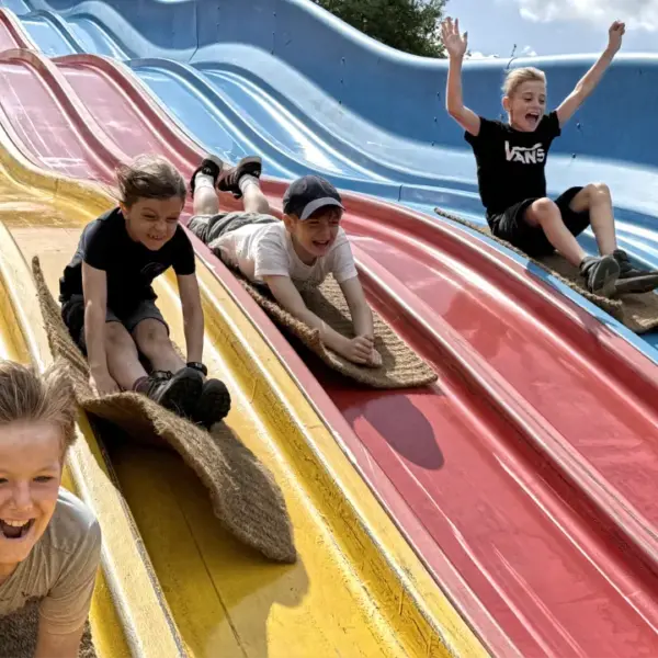 Kinder auf der Teppichrutsche im Freizeitpark Schloss Beck, die auf Ferienbetreuung in den Sommerferien bei Deine Erlebnismacher angemeldet sind.