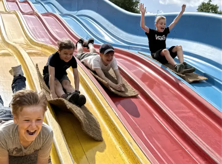 Ferienfreizeit-Essen-Ferienbetreuung-Sommer-Freizeitpark-Schloss Beck Kinder auf der Teppichrutsche im Freizeitpark Schloss Beck, die auf Ferienbetreuung in den Sommerferien bei Deine Erlebnismacher angemeldet sind.