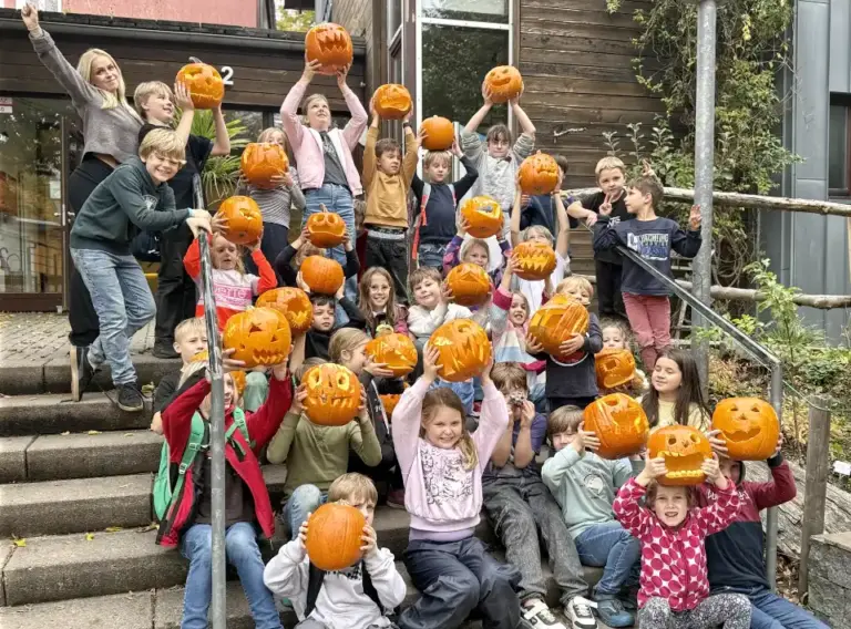 Ferienfreizeit-Herbst-Ferienbetreuung-Essen Kinder auf Ferienfreizeit bei Deine Erlebnismacher aus Essen mit selbstgeschnitzten Kürbissen in den Händen vor der DJH Jugendherberge Essen.
