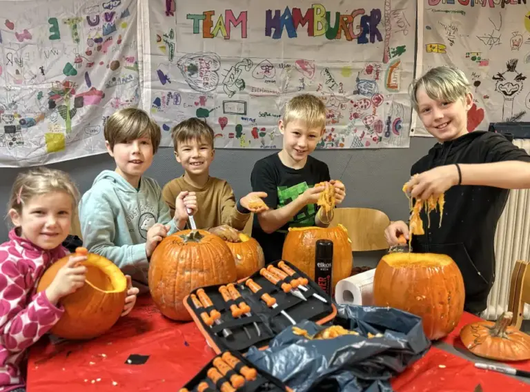 Ferienfreizeit-Herbstferien-Ferienbetreuung-Essen-Kürbisschnitzen Kinder beim Schnitzen von Kürbissen für Halloween auf der Ferienbetreuung Herbstferien in Essen von Deine Erlebnismacher.