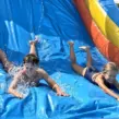 Kinder auf einer XXL-Wasserhüpfburg mit Riesenrutsche während der Ferienfreizeit Essen auf den Sommerferien.