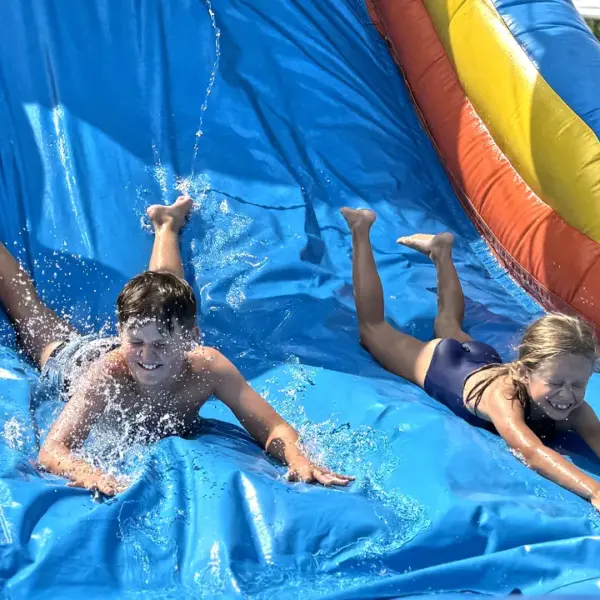 Kinder auf einer XXL-Wasserhüpfburg mit Riesenrutsche während der Ferienfreizeit Essen auf den Sommerferien.