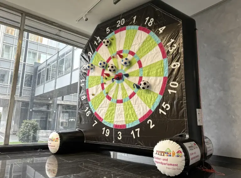 Fußball-Dart eckig 4 m – individuelles Event-Modul mit Klettbällen | Deine Erlebnismacher Aufblasbares Fußball-Dart-Modul in eckiger Form, 4 Meter hoch, individuell gestaltet für die Stadt Herdecke, mit Klett-Fußbällen und Filz-Wurfpfeilen, hergestellt von Deine Erlebnismacher