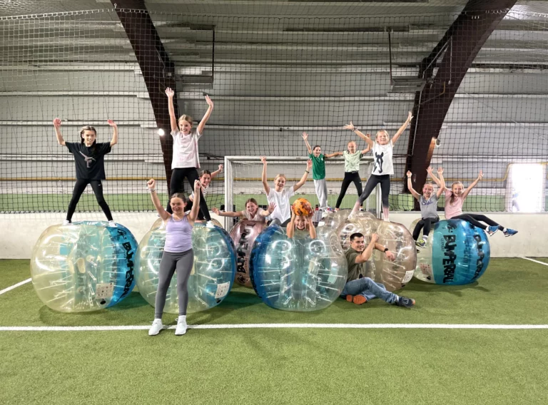 Eine Gruppe von Menschen posiert für ein Foto in aufblasbaren Bumper Balls auf einer Wiese.