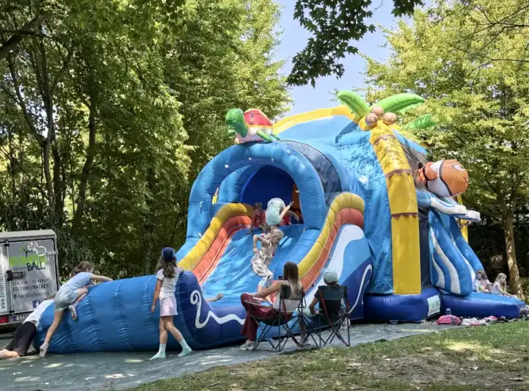 Huepfburg-mit-Wasser-Riesenrustche Spielende Kinder auf einer riesigen Hüpfburg mit XXL-Wasserrutsche aufgeblasen auf dem Gelände der DJH Jugendherberge in Essen Werden.