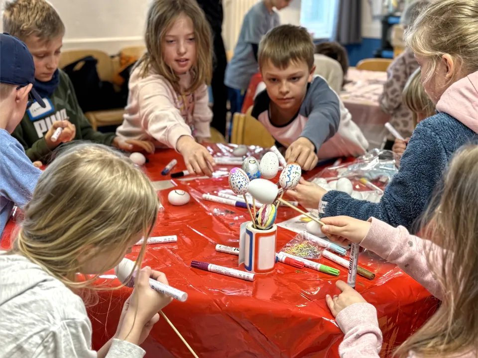 Kinder basteln gemeinsam kreative Osterdekorationen während der Osterferien bei einer betreuten Ferienfreizeit