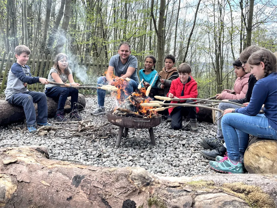 Kinder am Lagerfeuer auf Ferienfreizeit in der DJH-Jugendherberge in Essen, die Stockbrot backen mit den Erlebnismachern.