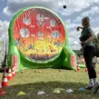 Aufgeblasenes Fußball-Darts mit einer riesigen Lochwand auf dem SMAG Sundance Festival 2025 am Seaside Beach Baldeney, wo eine junge Frau einen Ball auf das aufgeblasene Modul wirft.