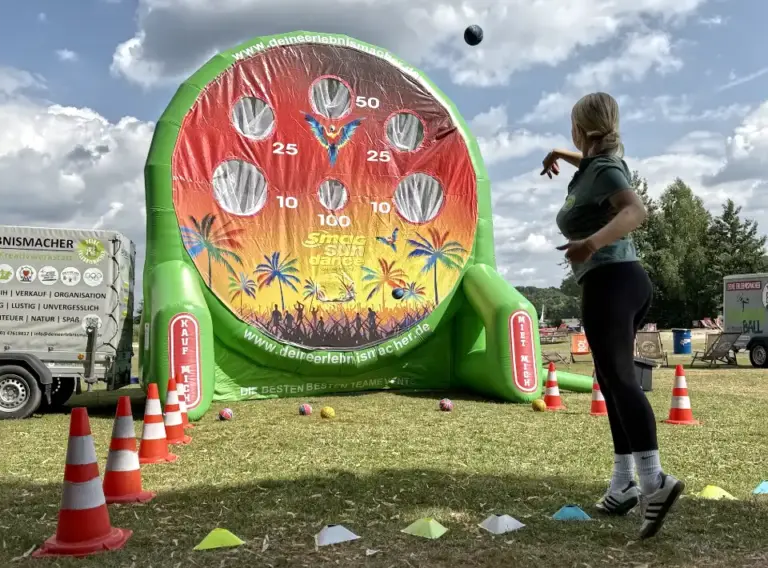 Lochwand-Fußballdarts-5.0-Meter-SMAG Sundance Festival Aufgeblasenes Fußball-Darts mit einer riesigen Lochwand auf dem SMAG Sundance Festival 2025 am Seaside Beach Baldeney, wo eine junge Frau einen Ball auf das aufgeblasene Modul wirft.