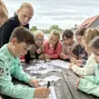 Schatzsuche für Kinder auf einem Kindergeburtstag, die an einem Tisch sitzen und ein Rätsel lösen.