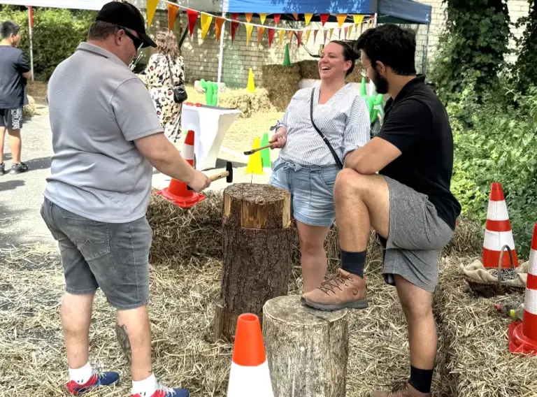 Sommerfest-Firmenfeier-Firmenfest-Teambuilding-Westerncity-Nageln-Nagelbock-Wettnageln-Haemmern Menschen am Nagelbock auf dem Sommerfest "Jahrmarkt".