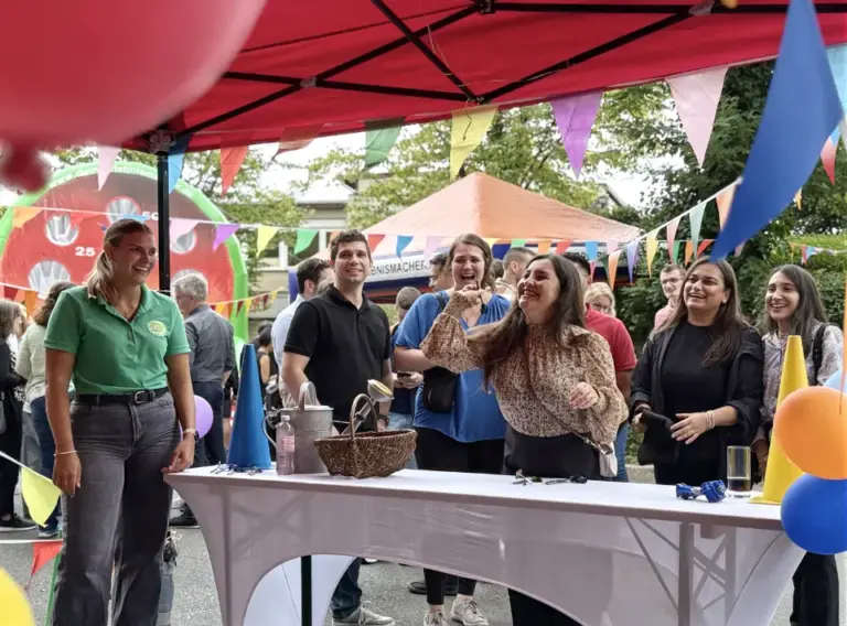 Sommerfest-Jahrmarkt-Teambuilding-Event-Firmenfeier-Pfeilewerfen-Mieten Mitarbeiter:Innen beim Pfeilewerfen auf dem Sommerfest "Jahrmarkt" mit verschiedenen Ständen von der Kirmes.