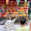 Kinder beim Pfeilewerfen auf aufgeblasene Luftballons als Mitmachstation auf dem Sommerfest "Jahrmarkt" der Firma Moldino in Hilden.