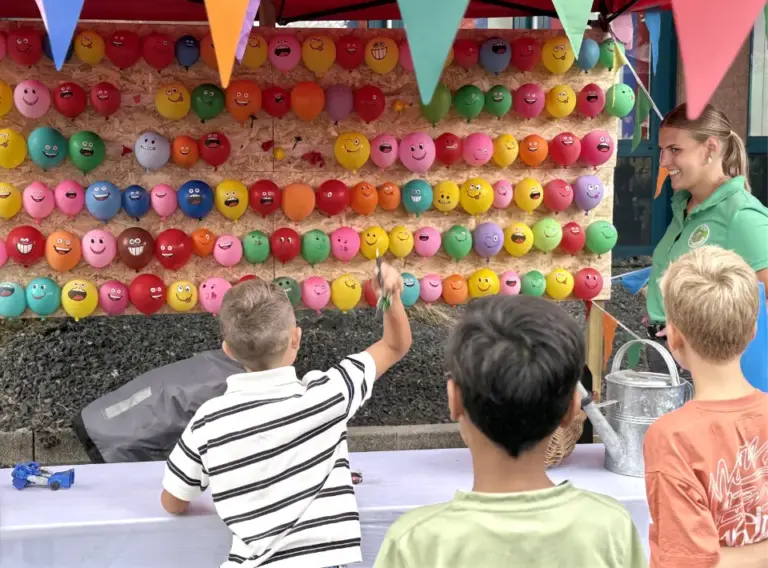 Sommerfest-Jahrmarkt-Teambuilding-Event-Firmenfeier-Pfeilewerfen-Mieten-Kindergeburtstag Kinder beim Pfeilewerfen auf aufgeblasene Luftballons als Mitmachstation auf dem Sommerfest "Jahrmarkt" der Firma Moldino in Hilden.