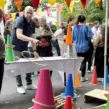 Menschen auf Firmenfeier beim Teambuilding-Event Jahrmarkt mit verschiedenen Jahrmarktständen, insbesondere Ringewerfen.