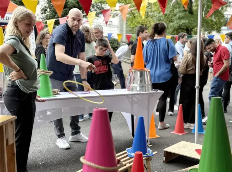 Sommerfest-Jahrmarkt-Teambuilding-Event-Firmenfeier-Ringewerfen-Mieten Menschen auf Firmenfeier beim Teambuilding-Event Jahrmarkt mit verschiedenen Jahrmarktständen, insbesondere Ringewerfen.
