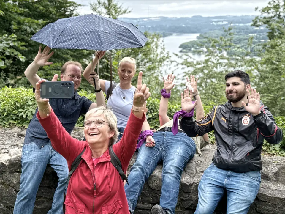 Personen beim Teambuilding Event Schnitzeljagd als Firmenfeier am Baldeneysee in Essen, die an der Ruine Isenburg ein Selfie als Gruppenfoto machen.