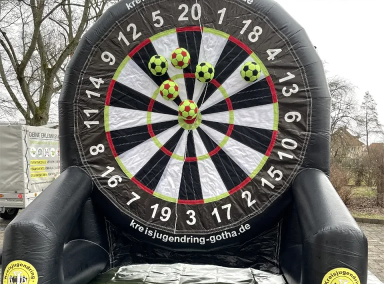 Verkauf-Fußballdarts-Fussballdart-Kaufen-Fußball-Dart-Lochwand-KJR-Gotha Schwarzes, aufgebautes Fußballdart vom KJR Gotha mit Klettbällen auf einer Klettwand in der Gestalt eines Dartspiels