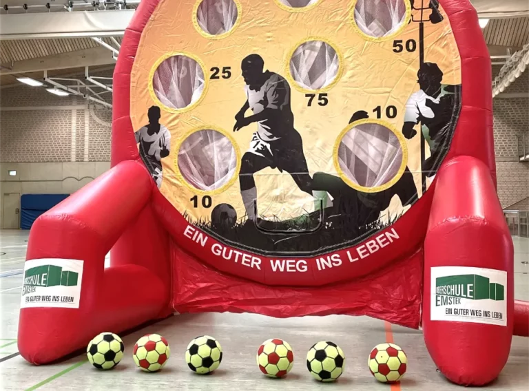 Verkauf-Fußballdarts-Fussballdart-Kaufen-Fußball-Dart-Torwand-Oberschule-Emstek 6 Klettbälle vor einem roten Fussball Darts Modul liegend in der Turnhalle der Oberschule Emstek