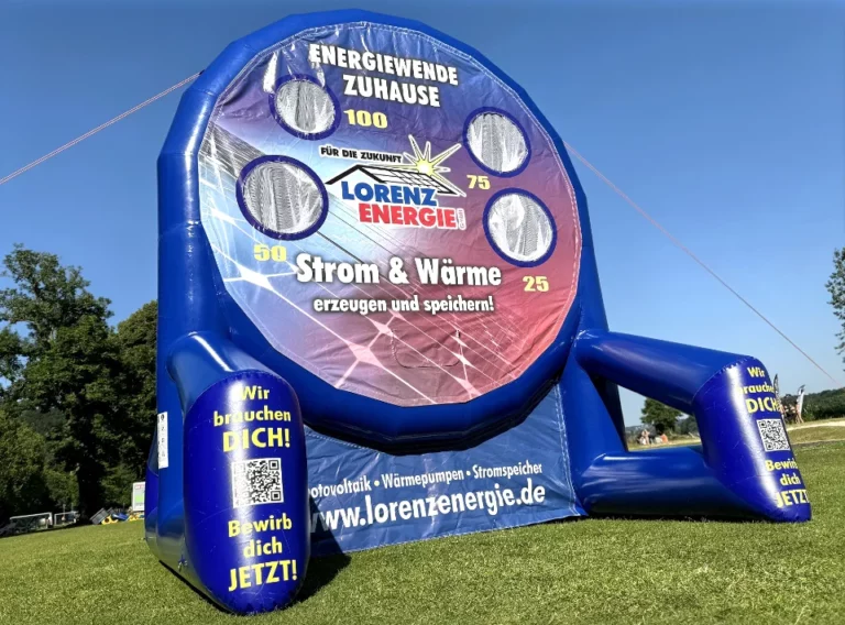 Verkauf-Fußballdarts-Fussballdart-Kaufen-Produktion-Fußball-Dart-Torwand-Lorenzenergie Dunkelblaues Eventmodul aufgeblasen auf einer Wiese mit einer Spielfläche im Designe einer Lochwand