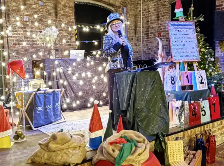 Moderierte Weihnachtsfeier QuizShow – Interaktives Teambuilding Firmenevent im Winter Moderatorin führt durch eine Weihnachtsfeier QuizShow auf der Bühne als Teambuilding Firmenevent.