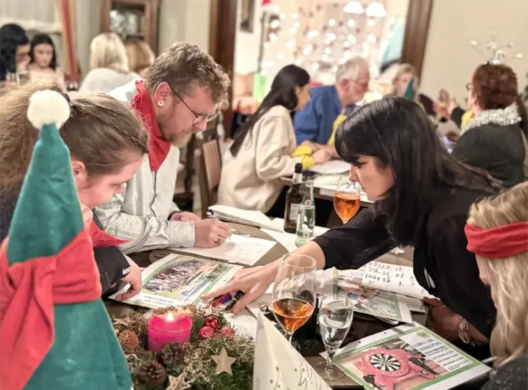 Interaktive Quizshow zur Weihnachtsfeier – Teambuilding mit Spaß und Spannung Team arbeitet gemeinsam an Quizfragen bei einer Firmen-Weihnachtsfeier mit interaktivem Quizshow-Teamevent