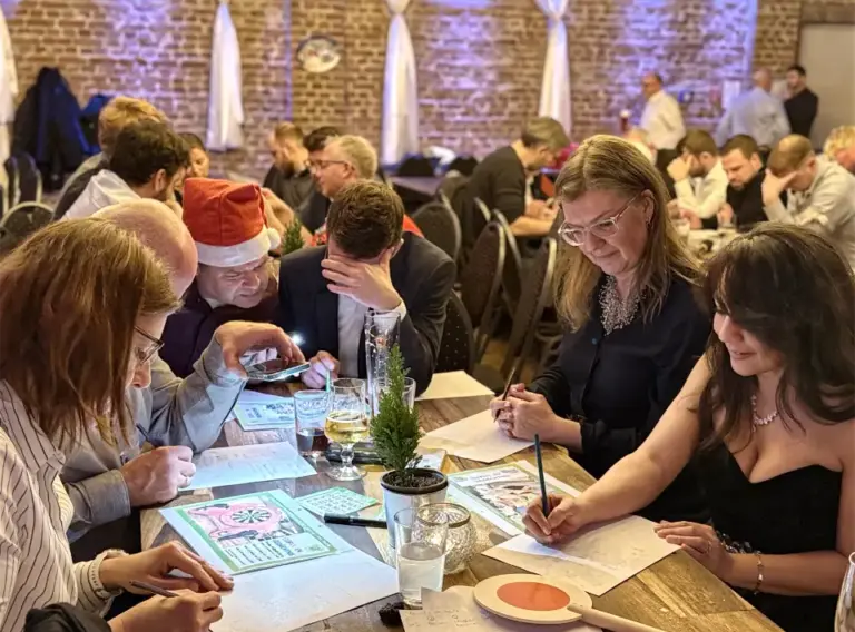 Weihnachtsfeier QuizShow am Tisch – Interaktives Teambuilding für Firmen Teilnehmer einer Weihnachtsfeier QuizShow arbeiten gemeinsam an Quizaufgaben bei einem Teambuilding Event.
