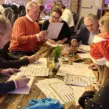 Teilnehmer einer Weihnachtsfeier QuizShow lösen gemeinsam Quizfragen als Teambuilding Event am Tisch.