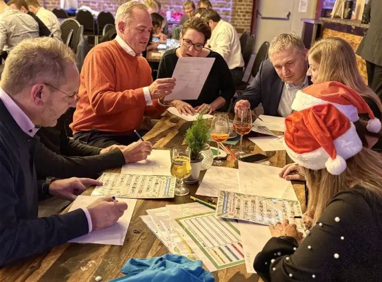 Weihnachtsfeier Quizshow als Teambuilding – Interaktives Firmenevent im Winter Teilnehmer einer Weihnachtsfeier QuizShow lösen gemeinsam Quizfragen als Teambuilding Event am Tisch.