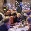 Teilnehmer einer Weihnachtsfeier QuizShow arbeiten gemeinsam an Quizfragen bei einem Teambuilding Event.
