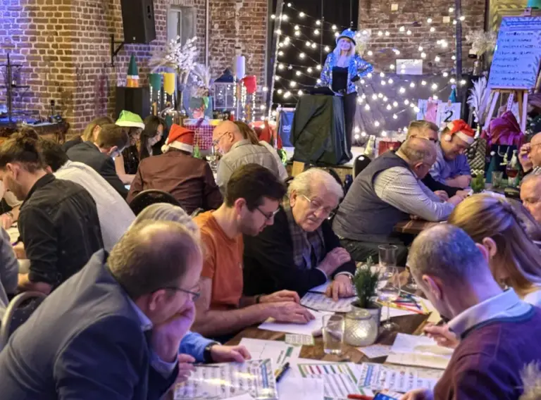 Weihnachtsfeier QuizShow mit Moderatorin – Interaktives Teambuilding Firmenevent Teilnehmer einer Weihnachtsfeier QuizShow arbeiten gemeinsam an Quizfragen bei einem Teambuilding Event.