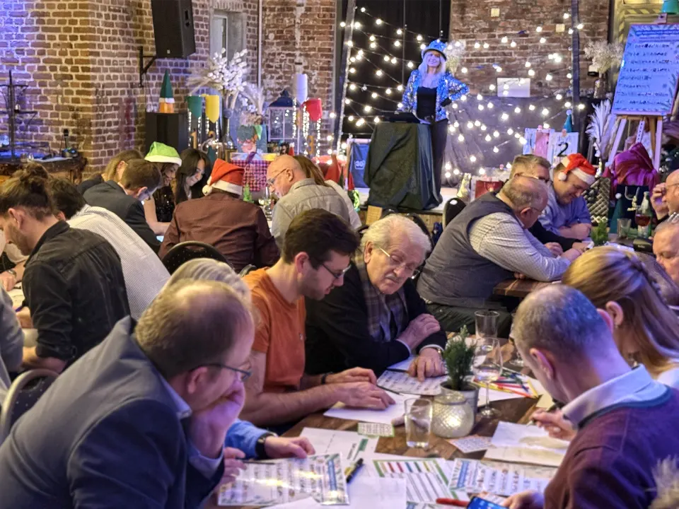Teilnehmer einer Weihnachtsfeier QuizShow arbeiten gemeinsam an Quizfragen bei einem Teambuilding Event.