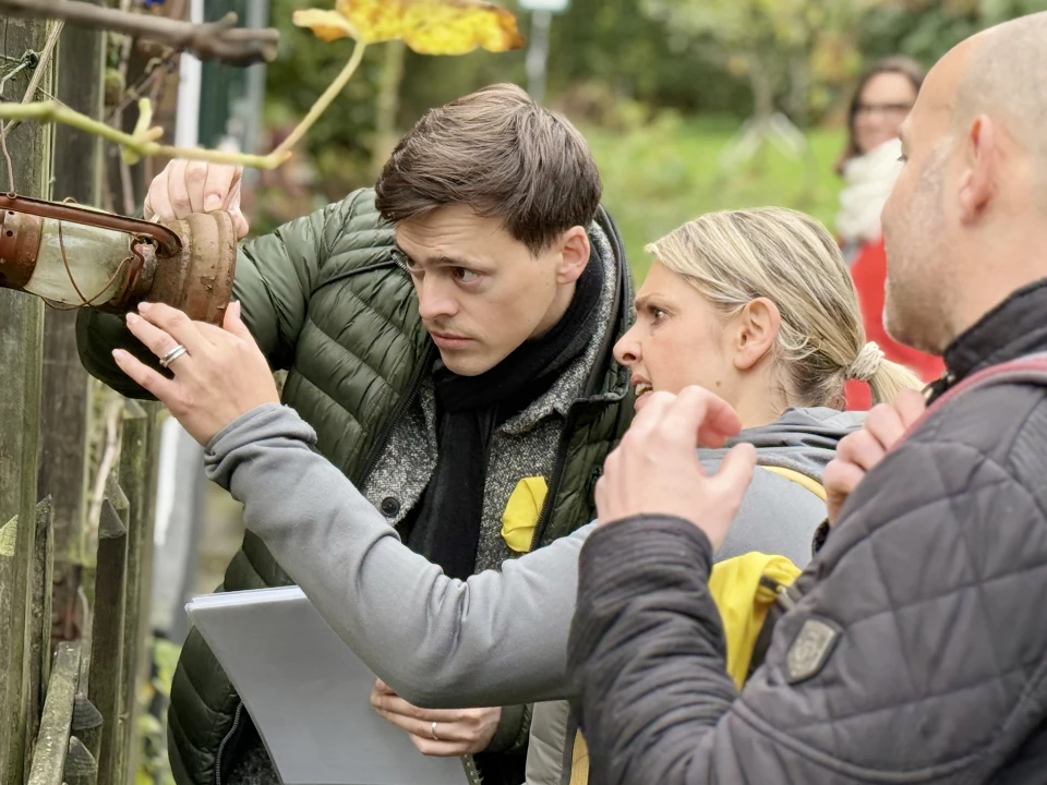 Arbeitskollegen auf einer Schnitzeljagd zur Weihnachtsfeier in Essen, die in der Natur ein Windlicht genauer betrachten, um die gesuchte Lösung zu finden.