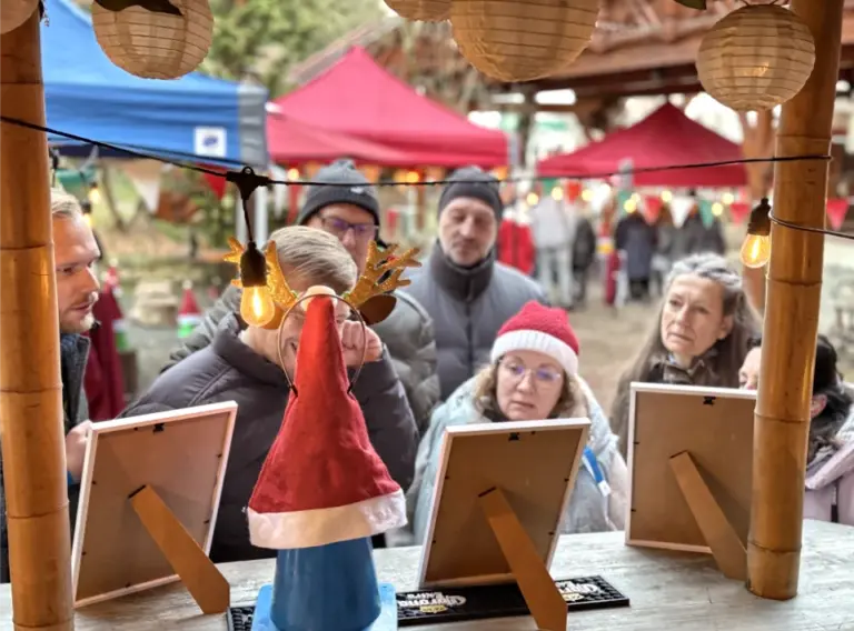 Rätselstation bei Winterolympiade auf einer weihnachtlichen Firmenfeier Teilnehmende lösen Aufgaben an einer Rätselstation bei einer winterlichen Firmenfeier im Außenbereich.