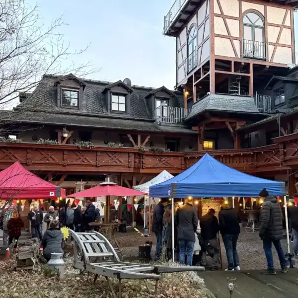 Wintermarkt-Location mit Pavillons, Lichterketten und Gästen bei einer weihnachtlichen Firmenfeier und Winterolympiade.