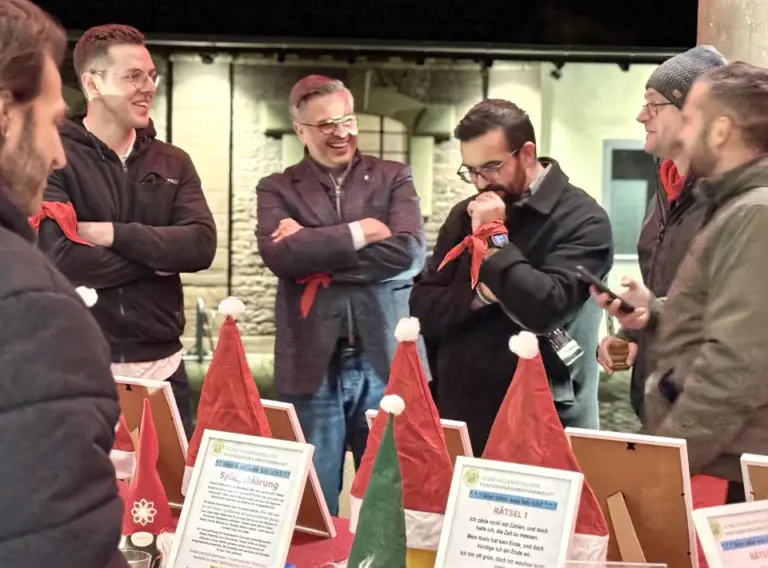 Winter Olympiade Weihnachtsfeier – Rätselstation beim Teambuilding-Event in Karlsruhe Teilnehmer einer Winter Olympiade während einer deutschlandweit angebotenen Teambuilding-Weihnachtsfeier in Karlsruhe stehen an einer Rätselstation und tauschen sich aus.