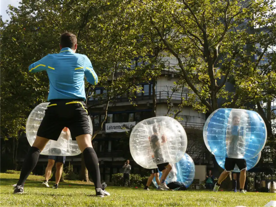 Schiedsrichter betreut ein Bumper Ball Kindergeburtstag Event mit Bubble Soccer Bällen auf einer Outdoor-Fläche in Essen.